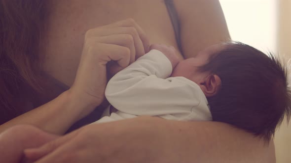 Mom breastfeeds a nursing baby. Close-up portrait of the infant and mother.