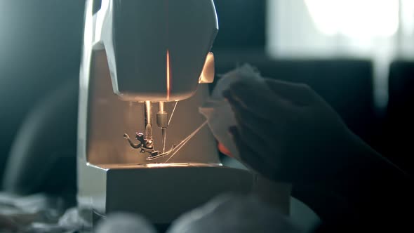 Hands of a Young Woman Seamstress Sewing a White Cloth and Cutting the Thread