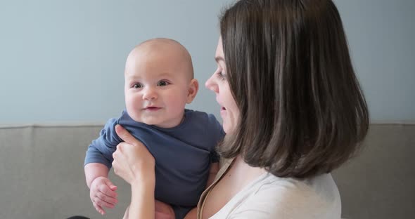 Beautiful Young Mother Holding Little Son in Arms, Woman and Child Laughing