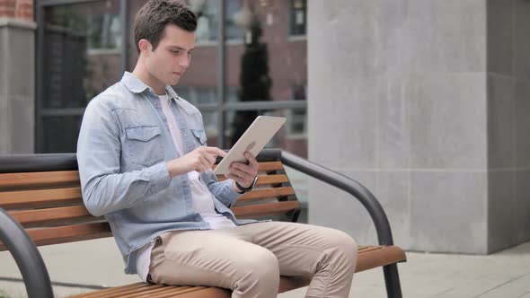 Outdoor Young Man Upset by Loss on Tablet