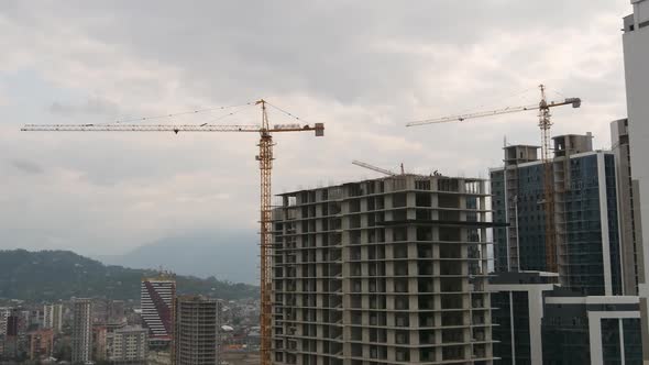 Building Construction. Tower Crane on a Construction Site Lifts a Load at High-rise Building