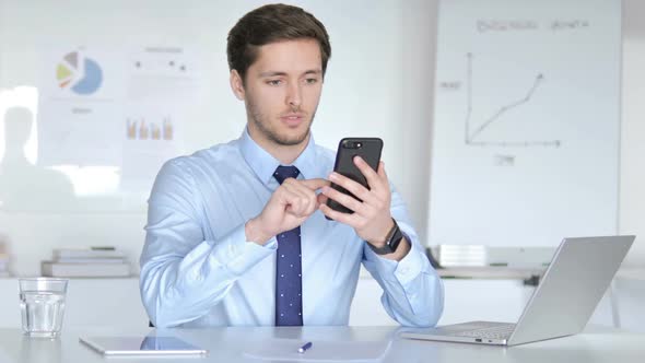 Young Businessman Celebrating Success on Smartphone