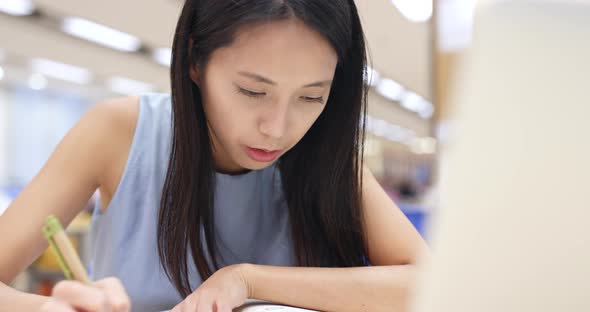 Woman working on her homework in university library 