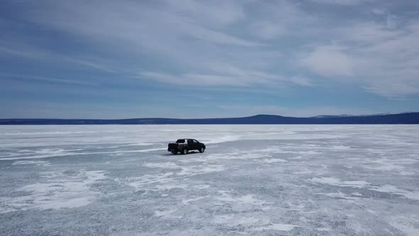 Drone Aerial View of Car in Winter Landscape and Hi Speed Driving Over the Frozen Lake