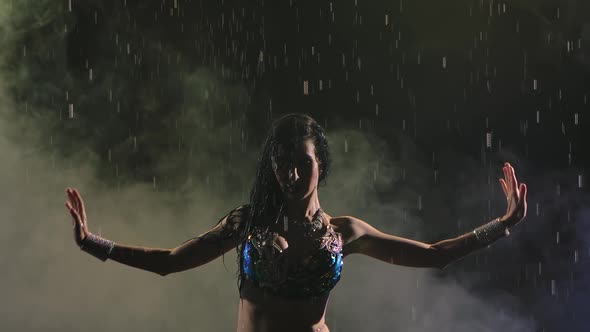 Silhouette of Oriental Beauty Dancing Belly Dance in the Rain. Woman with Attractive Body