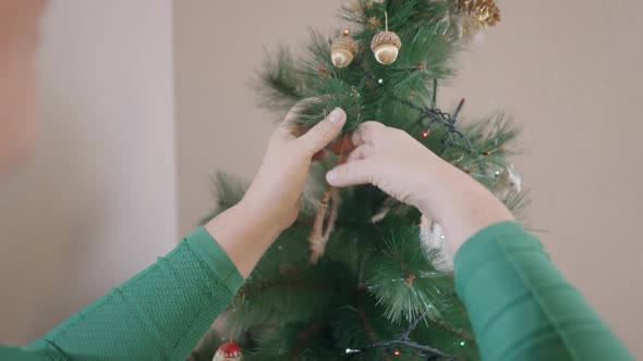 Old Caucasian Woman Hanging Ornaments On Christmas Tree