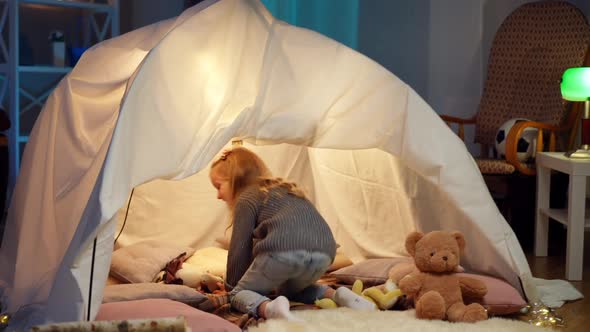 Tracking Shot of Cheerful Little Girl Running to Tent in Living Room Sitting Inside