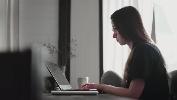 A young man and a young girl are working in front of laptops in their bright apartment.