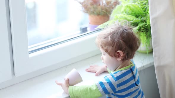 little boy plays on the windowsill at home