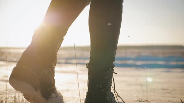 Female Feet in Black Boots Winter Walking in Snow