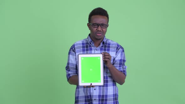 Stressed Young African Hipster Man Talking While Showing Digital Tablet