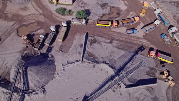 Excavators and Tractors Load Crushed Stone and Rock Into Dump Trucks