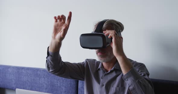 Caucasian businessman sitting on couch using vr googles in office