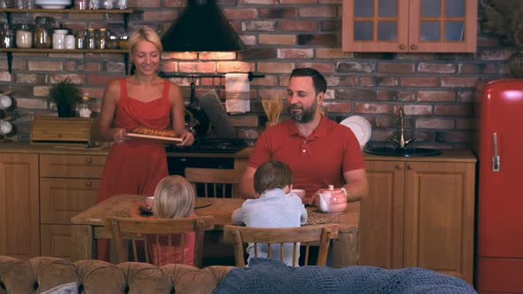 Friendly Family Mom Dad and Two Children Gathered at the Dinner Table and Mom Baked a Pie for Dinner