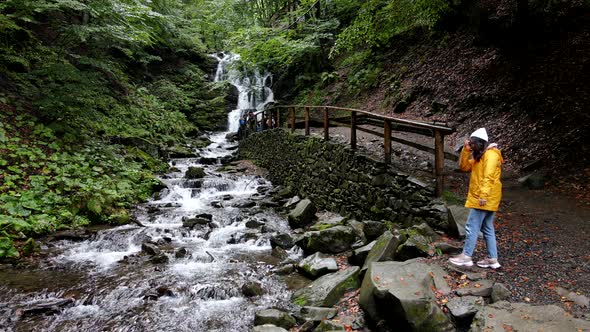 Woman Hiker Near Waterfall Yellow Raincoat