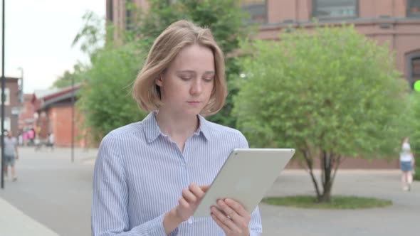 Woman Working on Tablet While Walking in Street