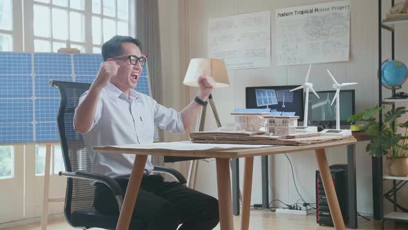 Side View Of Asian Man Being Happy Succeed Building A Model Of Small House With Solar Panel