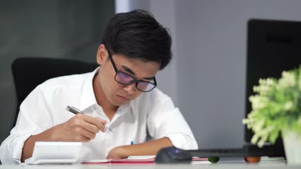 young man studying and writing on notebook with laptop computer