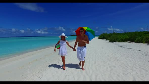 Family of two sunbathe on luxury tourist beach break by blue lagoon with white sandy background of t