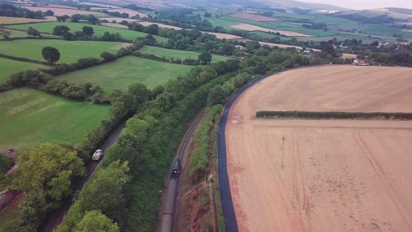 Panning and tracking aerial of a steam training through a busy countryside landscape surrounded by t