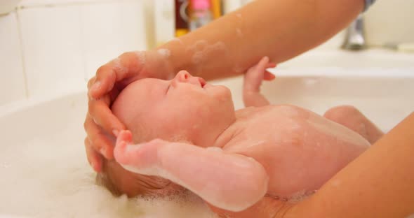 Mother giving her baby boy a bath in bathroom 4k