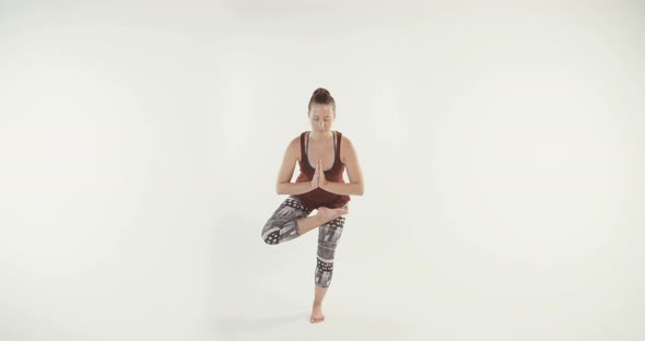 Young attractive woman performing Yoga routine on a white studio background
