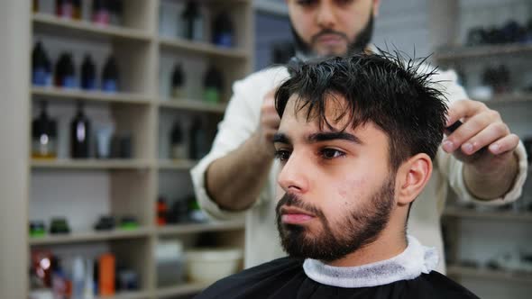 Barber Sprinkles Water and Combs the Hair of a Client in a Barbershop