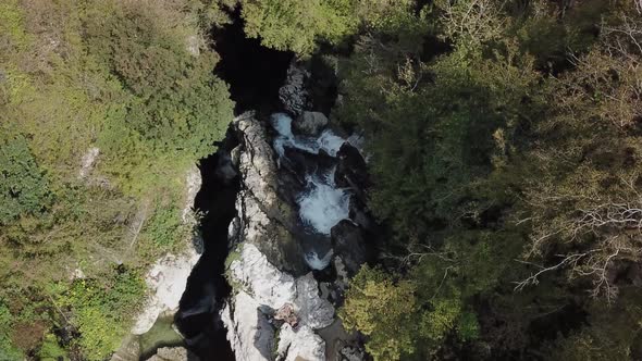 Top view of the mountain river with a small waterfall. White stones and blue, clear water. Untouched