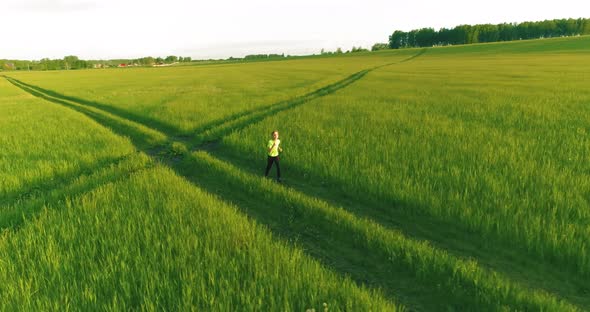 Sporty Child Runs Through a Green Wheat Field. Evening Sport Training Exercises at Rural Meadow. A