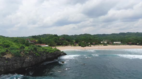 Aerial panorama of scenic Krakal coast with golden sand beach and volcanic cliff