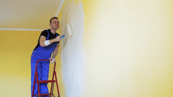 Caucasian man paints the wall with roller