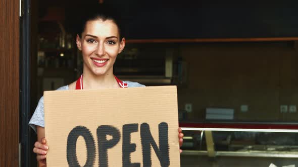 Female baker holding open signboard