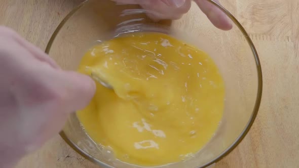 Slow Motion Shot of Whisking Eggs With a Fork in the Kitchen