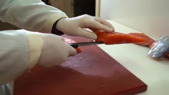 salmon industry worker in white coating salmon filet from chopboard to cutting table - slow motion