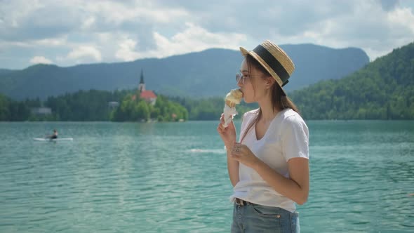 Young Woman is Eating Ice Cream on Shore of Lake Bled in Slovenia