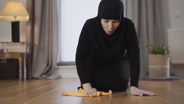 Close-up of Young Muslim Lady in Hijab Cleaning the Floor with Yellow Rag. Diligent Eastern