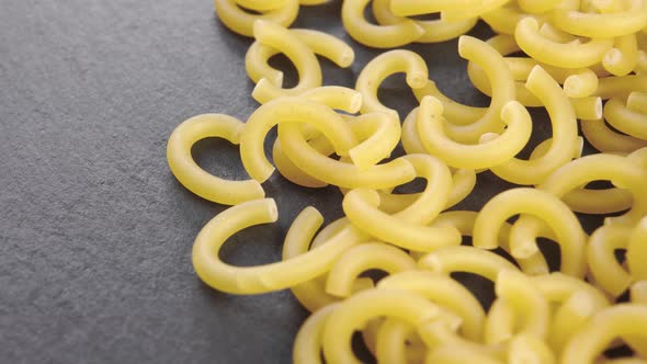Dry Italian Gobbetti pasta on a stone black slate surface. Macro. Slow rotation
