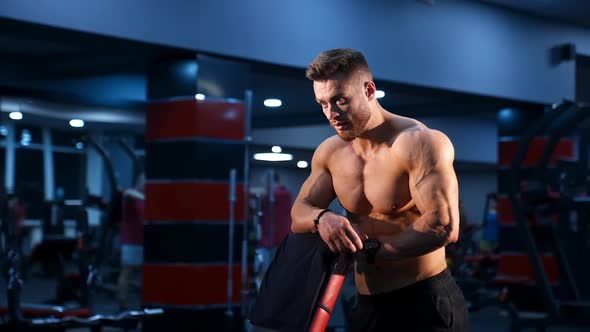 Muscular male athlete with naked torso in gym. 