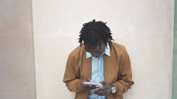 Happy Modern Black African Guy typing on smartphone	