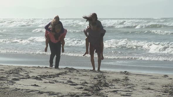 LS OF TWO YOUNG MEN RUNNING WITH YOUNG WOMEN ON THEIR BACKS