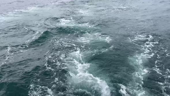 Plume of bubbles forming in the back of a sailing boat on gloomy day