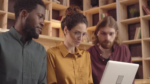 Three Multiethnic Creative Colleagues Using Laptop in Coworking