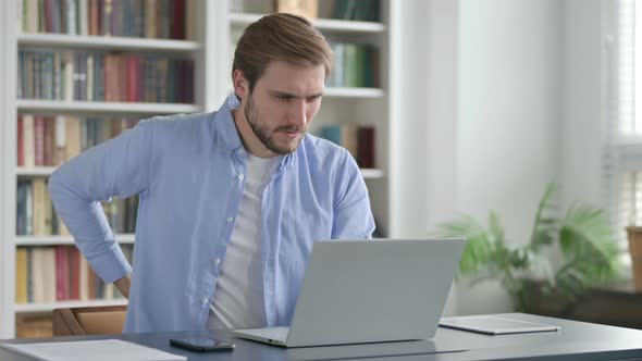 Man Having Back Pain While Using Laptop in Office