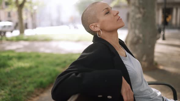 Handsome bald woman sitting on the bench