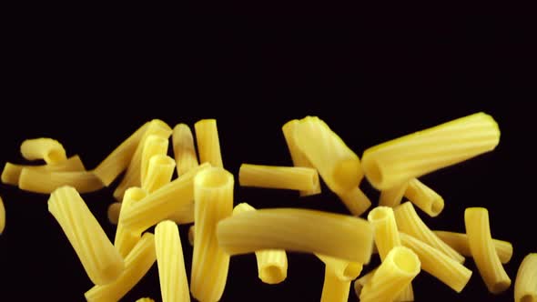 Pasta Rigatoni Flies Up on a Black Background