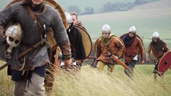 Group of Viking with Shields Walking Forward on the Meadow