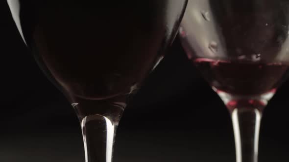 Pouring wine two glasses dark background close up shot