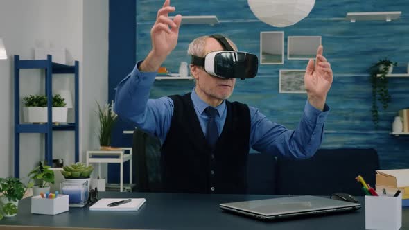 Senior Man Using Virtual Reality Goggles in Living Room Gesturing