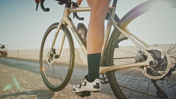 Legs of Unknown Young Girl in Cycling Shoes and Sportswear Who is Riding a Bike Along Sea Embankment