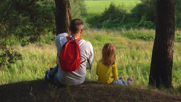 Father and Child in Forest at Sunset Look at Landscape